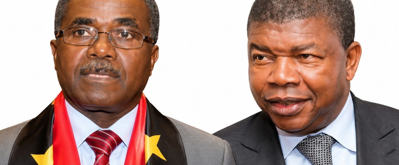 À esquerda, Julião Mateus Paulo "Dino Matross" usa óculos, bigode, um fato cinzento e uma gravata vermelha às riscas, acompanhado por uma écharpe preta e vermelha com estrelas amarelas associada ao MPLA. À direita, o Presidente João Lourenço surge de fato escuro, camisa azul-clara e gravata cinzenta com padrões pretos, com o olhar direcionado para a sua direita.